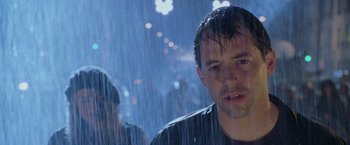 Movie still from “Godzilla” (1998), directed by Roland Emmerich – A man with wet hair standing in the rain at night; Close Up shot, Over the shoulder angle