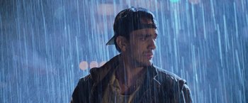 Movie still from “Godzilla” (1998), directed by Roland Emmerich – A man in a baseball cap standing in the rain; Close Up shot, Low angle
