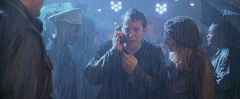 Movie still from “Godzilla” (1998), directed by Roland Emmerich – A man on a cell phone in the pouring rain; Medium shot, High angle