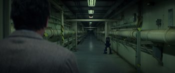 Movie still from “Godzilla” (2014), directed by Gareth Edwards – A man sitting in a room with pipes in the middle of the floor; Wide shot, High angle