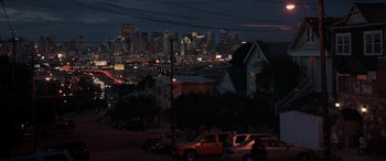 Movie still from “Godzilla” (2014), directed by Gareth Edwards – Cars parked on the side of the road in front of a city skyline at night; Extreme Wide shot, High angle