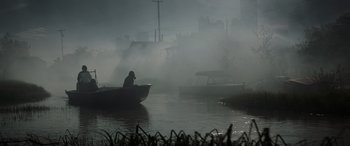 Movie still from “Godzilla” (2014), directed by Gareth Edwards – A man sitting in a boat on a body of water; Extreme Wide shot, High angle