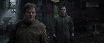 Movie still from “Godzilla” (2014), directed by Gareth Edwards – Two men standing next to each other in front of a building; Medium shot, Low angle