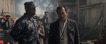 Movie still from “Godzilla” (2014), directed by Gareth Edwards – A group of men standing next to each other in front of a building; Medium shot, Over the shoulder angle