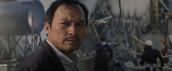Movie still from “Godzilla” (2014), directed by Gareth Edwards – A person wearing a suit and tie; Close Up shot, Low angle