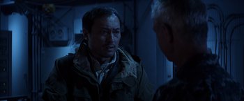 Movie still from “Godzilla” (2014), directed by Gareth Edwards – A man in a brown jacket talking to another man in a blue jacket; Close Up shot, Over the shoulder angle