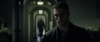 Movie still from “Godzilla” (2014), directed by Gareth Edwards – A man standing in a dark hallway with another man in the background; Close Up shot, Low angle