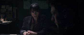 Movie still from “Godzilla” (2014), directed by Gareth Edwards – A woman sitting in front of a man in a dark room; Close Up shot, Over the shoulder angle