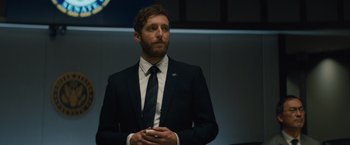 Movie still from “Godzilla: King of the Monsters” (2019), directed by Michael Dougherty – A man wearing a suit and tie standing in front of a wall; Close Up shot, Low angle