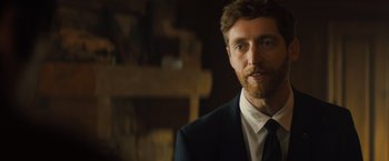 Movie still from “Godzilla: King of the Monsters” (2019), directed by Michael Dougherty – A person wearing a suit and tie; Close Up shot, Over the shoulder angle