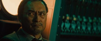 Movie still from “Godzilla: King of the Monsters” (2019), directed by Michael Dougherty – A person wearing glasses and a suit; Close Up shot, Low angle