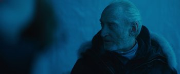 Movie still from “Godzilla: King of the Monsters” (2019), directed by Michael Dougherty – An older man wearing a black jacket and a fur coat; Close Up shot, Over the shoulder angle