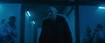 Movie still from “Godzilla: King of the Monsters” (2019), directed by Michael Dougherty – An older man wearing a black coat and a fur trimmed hood; Medium shot, Low angle