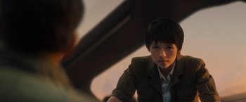 Movie still from “Godzilla: King of the Monsters” (2019), directed by Michael Dougherty – A woman sitting in front of an open window; Close Up shot, Over the shoulder angle