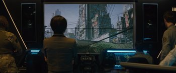 Movie still from “Godzilla: King of the Monsters” (2019), directed by Michael Dougherty – A person is looking at a large screen; Wide shot, Over the shoulder angle
