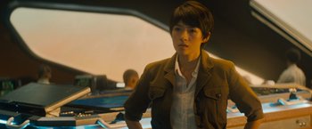 Movie still from “Godzilla: King of the Monsters” (2019), directed by Michael Dougherty – A man in a brown jacket standing in front of a desk; Medium shot, Over the shoulder angle