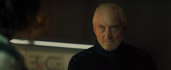 Movie still from “Godzilla: King of the Monsters” (2019), directed by Michael Dougherty – An old man with a beard and a black jacket; Close Up shot, Low angle