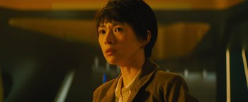 Movie still from “Godzilla: King of the Monsters” (2019), directed by Michael Dougherty – A woman in a brown jacket looking at the camera; Close Up shot, Low angle