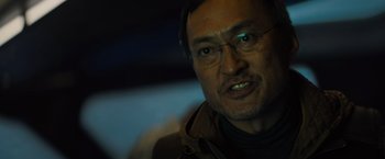Movie still from “Godzilla: King of the Monsters” (2019), directed by Michael Dougherty – A person wearing glasses and a jacket; Close Up shot, Low angle