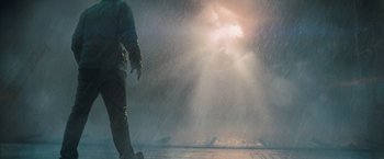 Movie still from “Godzilla: King of the Monsters” (2019), directed by Michael Dougherty – A man standing in the rain with a light shining on him; Wide shot, Low angle