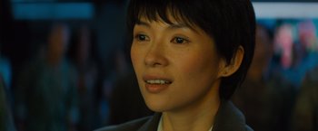 Movie still from “Godzilla: King of the Monsters” (2019), directed by Michael Dougherty – A woman's face in a suit jacket; Close Up shot, Over the shoulder angle