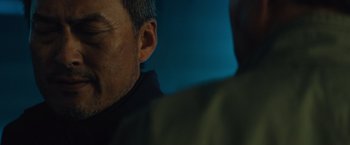 Movie still from “Godzilla: King of the Monsters” (2019), directed by Michael Dougherty – A man's face with a blue background; Close Up shot, Over the shoulder angle
