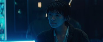 Movie still from “Godzilla: King of the Monsters” (2019), directed by Michael Dougherty – A person with short hair is standing in the dark; Close Up shot, Over the shoulder angle