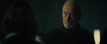 Movie still from “Godzilla: King of the Monsters” (2019), directed by Michael Dougherty – An older man is looking at the camera in the dark; Close Up shot, Over the shoulder angle