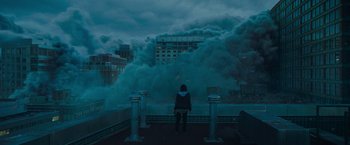 Movie still from “Godzilla: King of the Monsters” (2019), directed by Michael Dougherty – A person sitting on top of a bench near a building; Extreme Wide shot, Low angle