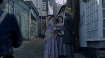Movie still from “Ammonite” (2020), directed by Francis Lee – A group of people standing next to each other on a street; Wide shot, Over the shoulder angle