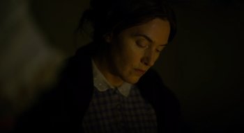 Movie still from “Ammonite” (2020), directed by Francis Lee – A woman with her eyes closed in a dark room; Close Up shot, High angle