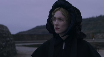 Movie still from “Ammonite” (2020), directed by Francis Lee – A woman wearing a black dress and a black hat; Close Up shot, Over the shoulder angle