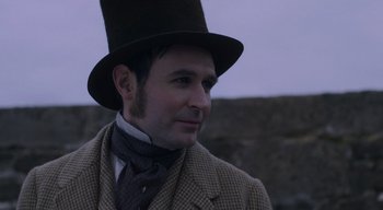 Movie still from “Ammonite” (2020), directed by Francis Lee – A man wearing a top hat and a suit; Close Up shot, Over the shoulder angle