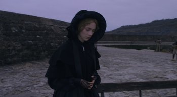 Movie still from “Ammonite” (2020), directed by Francis Lee – A woman in a long black dress and a black hat; Medium shot, Over the shoulder angle