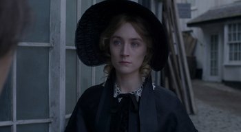 Movie still from “Ammonite” (2020), directed by Francis Lee – A woman wearing a black hat and a black coat; Close Up shot, High angle