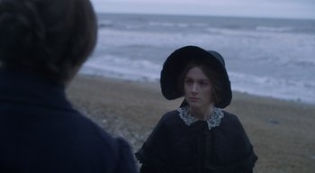 Movie still from “Ammonite” (2020), directed by Francis Lee – A woman in a black dress and a black hat; Close Up shot, Over the shoulder angle