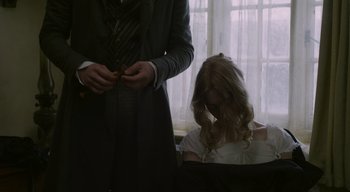 Movie still from “Ammonite” (2020), directed by Francis Lee – A man standing next to a woman in front of a window; Medium shot, Over the shoulder angle