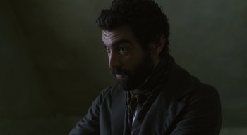 Movie still from “Ammonite” (2020), directed by Francis Lee – A man with a beard is sitting in a dark room; Close Up shot, High angle