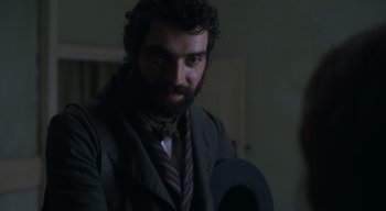 Movie still from “Ammonite” (2020), directed by Francis Lee – A man with a beard wearing a suit and tie; Close Up shot, Over the shoulder angle