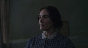 Movie still from “Ammonite” (2020), directed by Francis Lee – A woman in a plaid shirt looking to her left; Close Up shot, Low angle