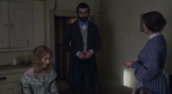 Movie still from “Ammonite” (2020), directed by Francis Lee – A man in a suit and a woman in a dress; Medium shot, High angle