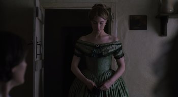 Movie still from “Ammonite” (2020), directed by Francis Lee – A woman in a green dress standing next to a door; Medium shot, Low angle