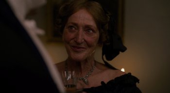 Movie still from “Ammonite” (2020), directed by Francis Lee – An older woman in a black dress holding a glass of wine; Close Up shot, Over the shoulder angle