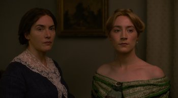 Movie still from “Ammonite” (2020), directed by Francis Lee – Two women standing next to each other in front of a painting; Close Up shot, Low angle