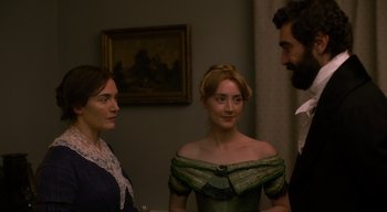 Movie still from “Ammonite” (2020), directed by Francis Lee – Two women and a man standing next to each other in a room; Medium shot, Over the shoulder angle