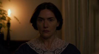 Movie still from “Ammonite” (2020), directed by Francis Lee – A woman in a dark room wearing a black dress; Close Up shot, Over the shoulder angle