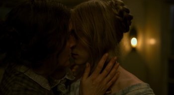 Movie still from “Ammonite” (2020), directed by Francis Lee – A man and a woman kissing each other in front of lights; Close Up shot, Over the shoulder angle