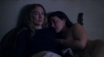 Movie still from “Ammonite” (2020), directed by Francis Lee – Two women in a dark room , one of whom is laying in bed and one of whom is sleeping; Medium shot, High angle