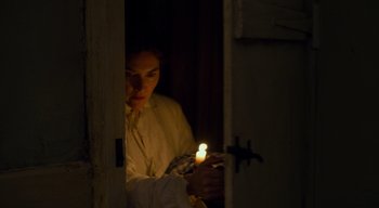 Movie still from “Ammonite” (2020), directed by Francis Lee – A person holding a candle in a dark room; Medium shot, High angle