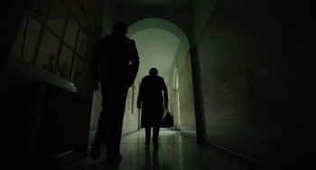 Movie still from “Golda” (2023), directed by Guy Nattiv – Two people are walking in a dark hallway; Wide shot, Low angle